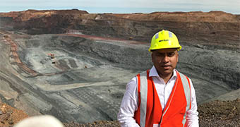 A man wearing a high vis vest and hard hat stands in front of a mind site