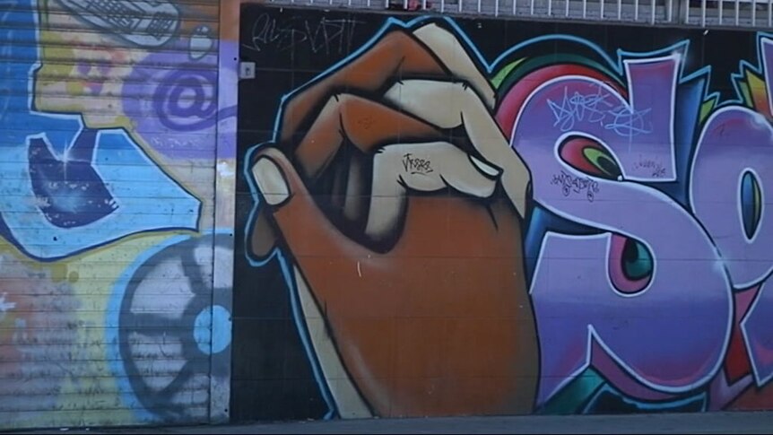 Graffiti shows dark and light skinned hands joined together