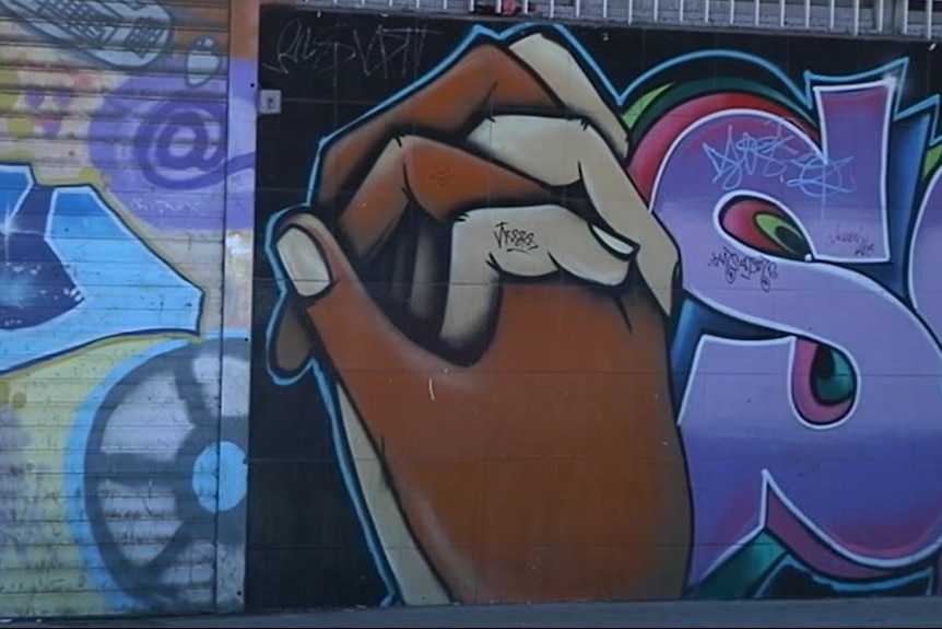 Graffiti shows dark and light skinned hands joined together