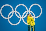Australian swimmers Emily Seebohm and Kaylee McKeown hug on the dais at the Tokyo Olympics, with the Olympic rings behind them.