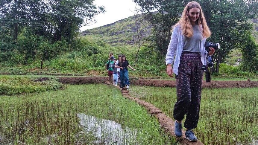 A teenager walks through rice paddies in Sri Lanka