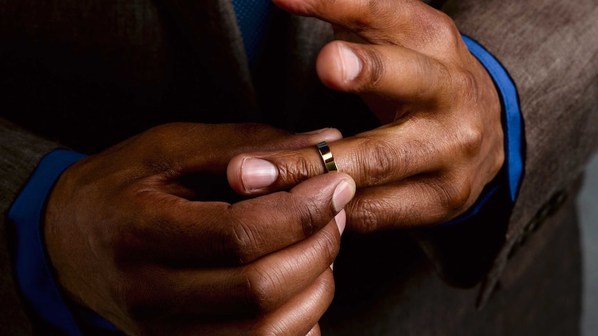 Close-up of a businessman's hands removing his wedding ring.