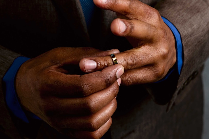 Close-up of a businessman's hands removing his wedding ring.