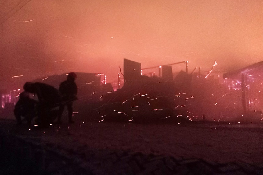 Plan nocturne d'un feu éclairé avec des étincelles de flammes dans un bidonville.