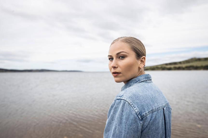 A woman wearing a blue shirt looks back over her shoulder towards the camera.