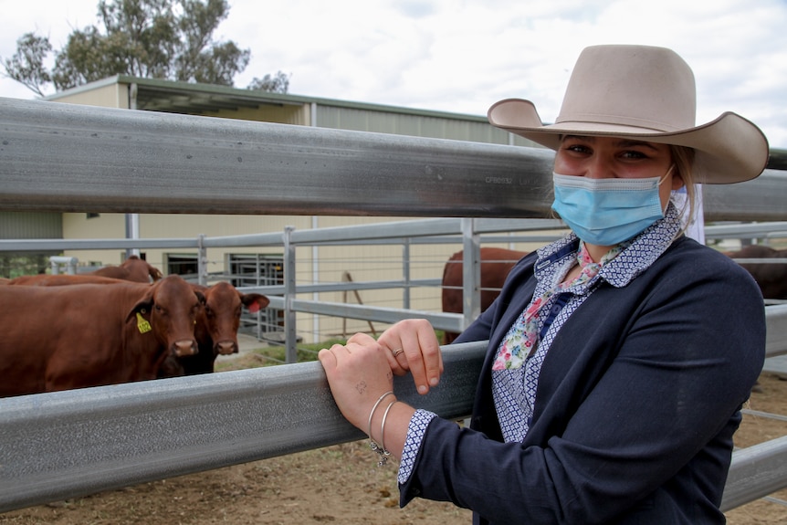 Georgia Perkins leans on the cattle pen holding her $9,000 cow.