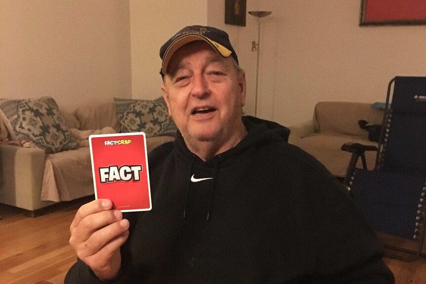 A older man holds up a card saying "Fact"