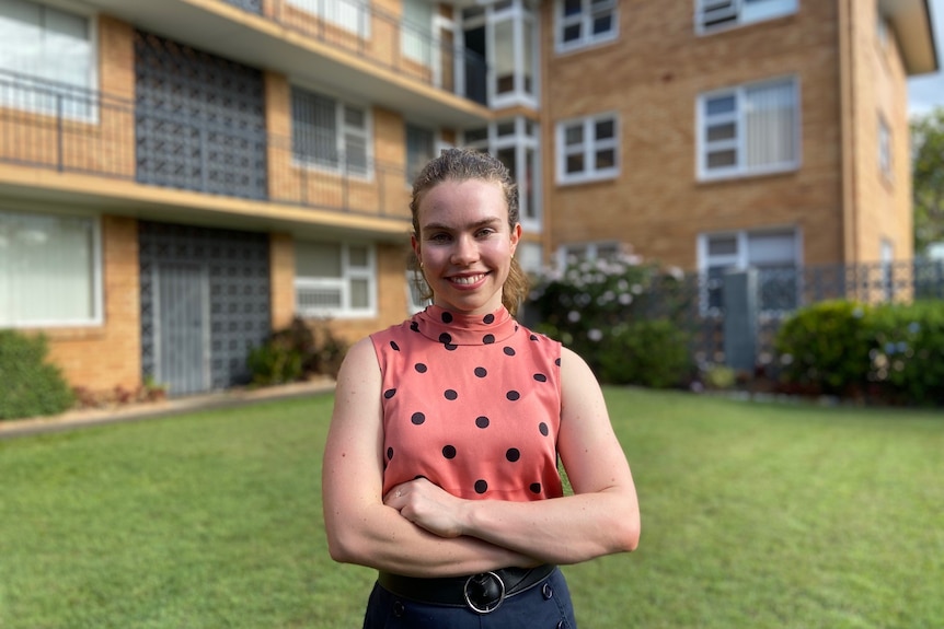 Lizzie stands in front of an apartment block