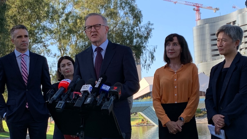 A man and three women stand behind anthony albanese speaking into the microphone