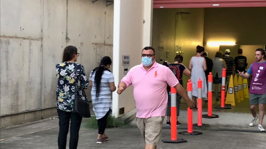 People, some wearing face masks, line up to vote at early polling centre in Brisbane.