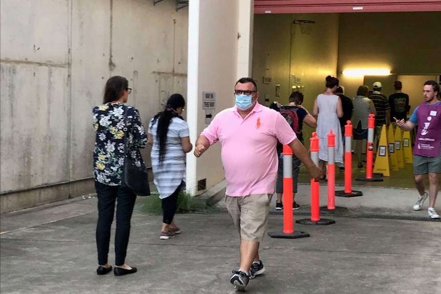 People, some wearing face masks, line up to vote at early polling centre in Brisbane.