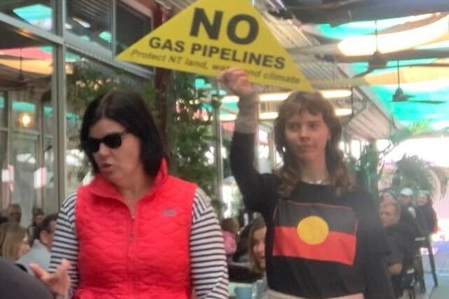 A woman with a fracking sign follows another woman