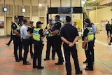 Police on the concourse of Flagstaff station under destination timetable screens.