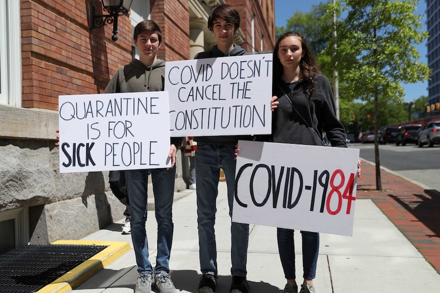 Three young people holding anti-coronavirus quarantine signs