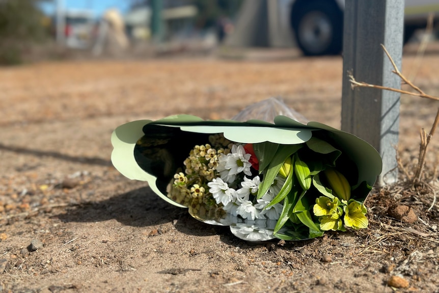 A bouquet of flowers lies on the ground in a small country town.