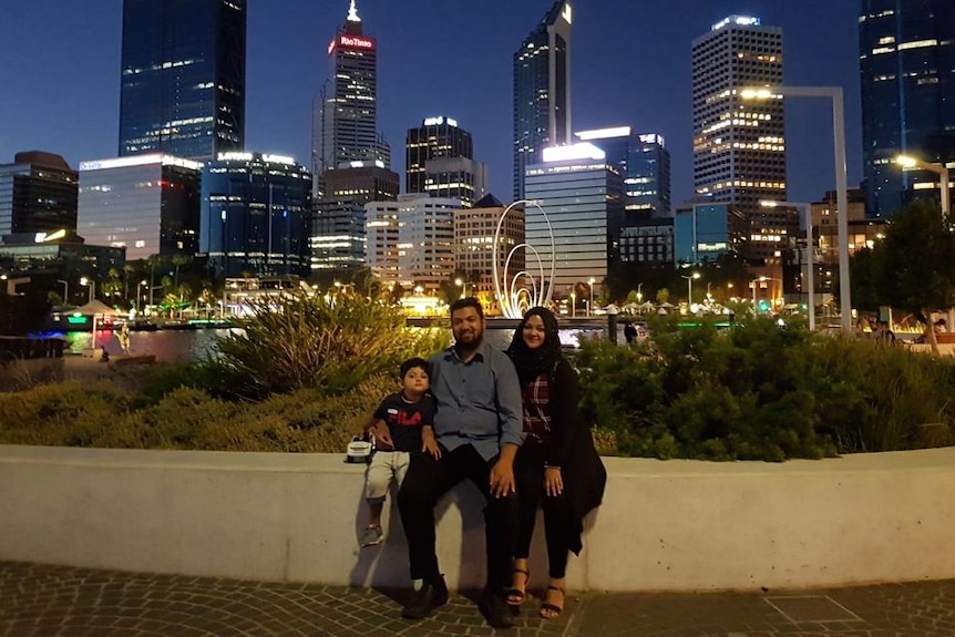 The family sits in front of a Perth skyline