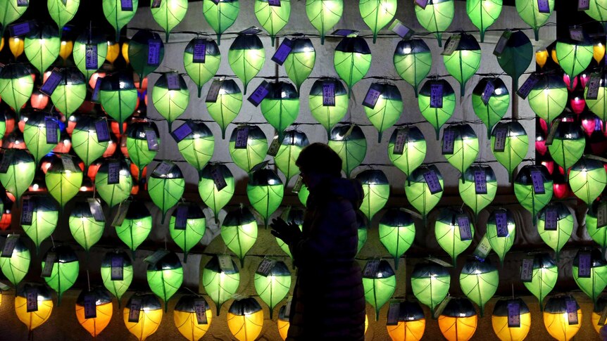 A woman prays in front of lanterns to celebrate the New Year at Jogyesa Buddhist temple in Seoul, South Korea