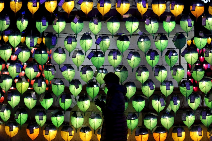 A woman prays in front of lanterns to celebrate the New Year at Jogyesa Buddhist temple in Seoul, South Korea