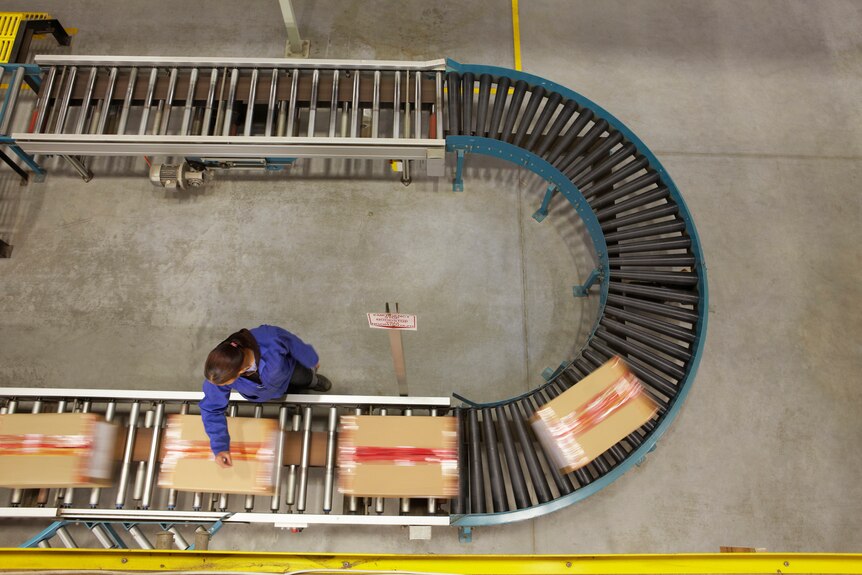 Birds eye view of a warehouse worker next to a conveyor belt.