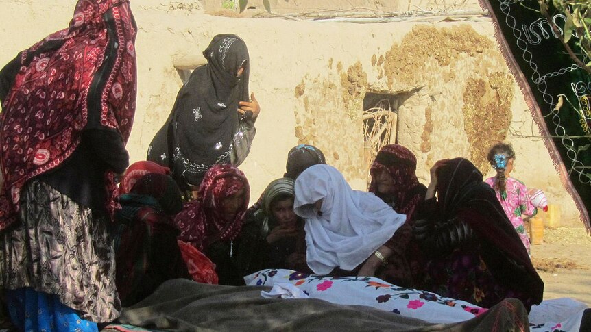 Afghan women cry over the bodies of civilians killed in a suicide attack in Baghlan province