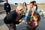 Julie Bishop leans down to accept flowers from a young girl.