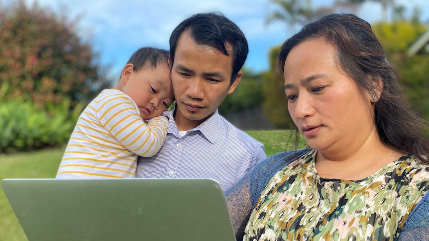 A woman is translating latest COVID-19 information to a  male member of the Myanmar community.