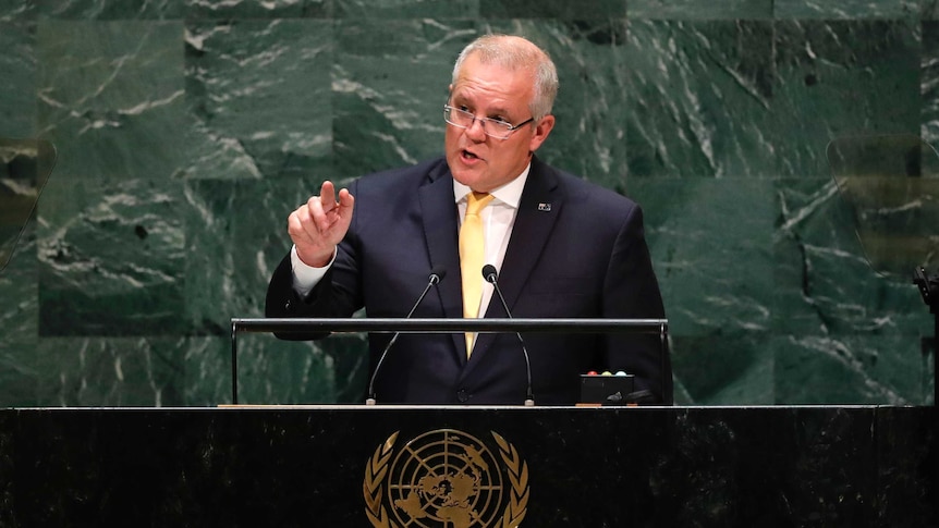 Australian Prime Minister Scott Morrison speaks at a lectern in front of a green background.