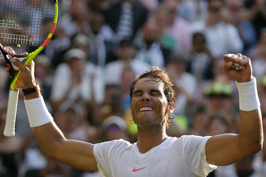 Rafa Nadal smiles with his hands aloft after a win.