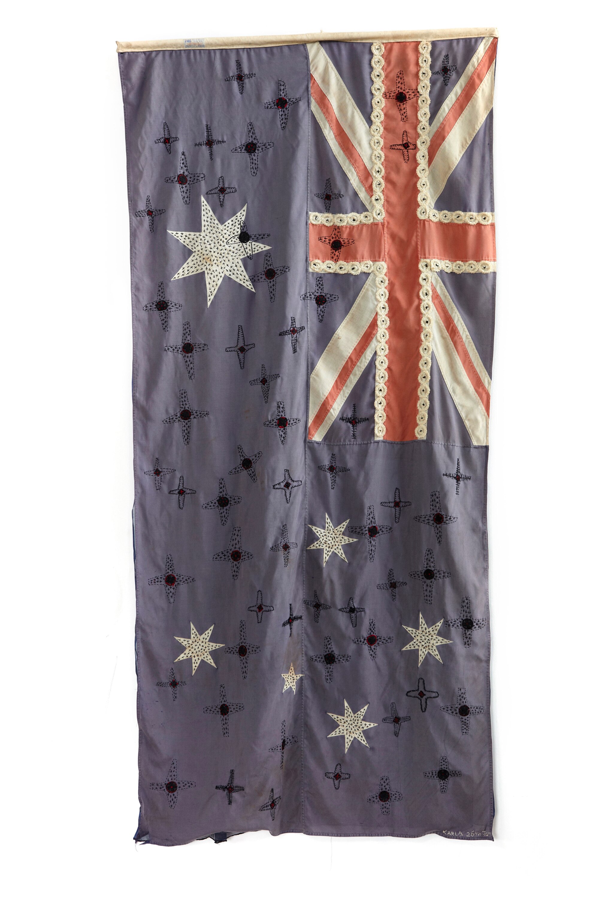 An old Australian flag onto which crosses, dots, stars and shell buttons are embroidered