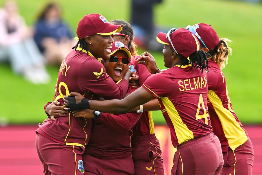 A group of West Indian cricketers embrace as they celebrate beating England.