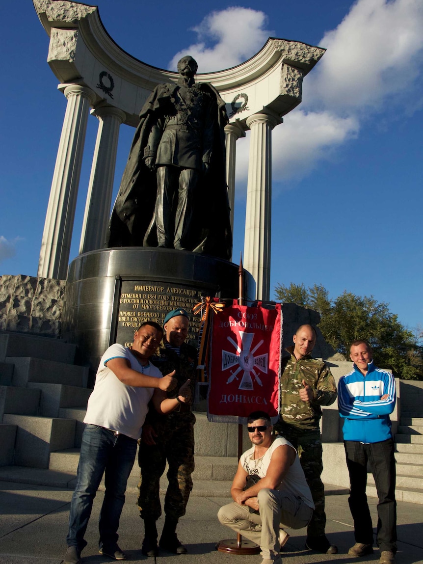 A group of uniformed Russians gather by a monument to Tsar Alexander II.