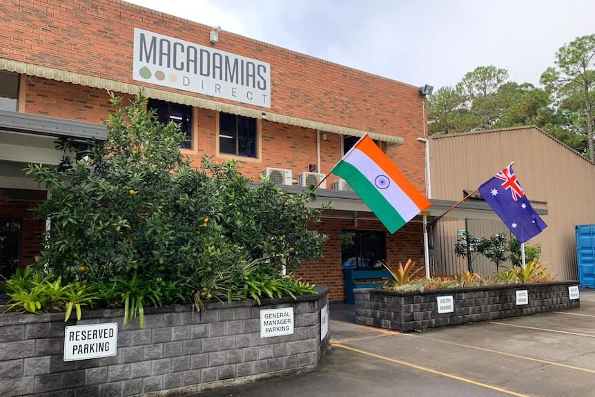 Indian and Australian flags fly outside a brick building.