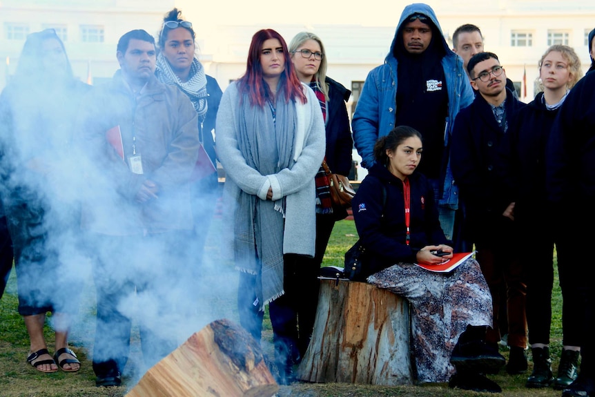 The delegates listen to Aunty Maureen Davis during a smoking ceremony at the Aboriginal Tent Embassy.