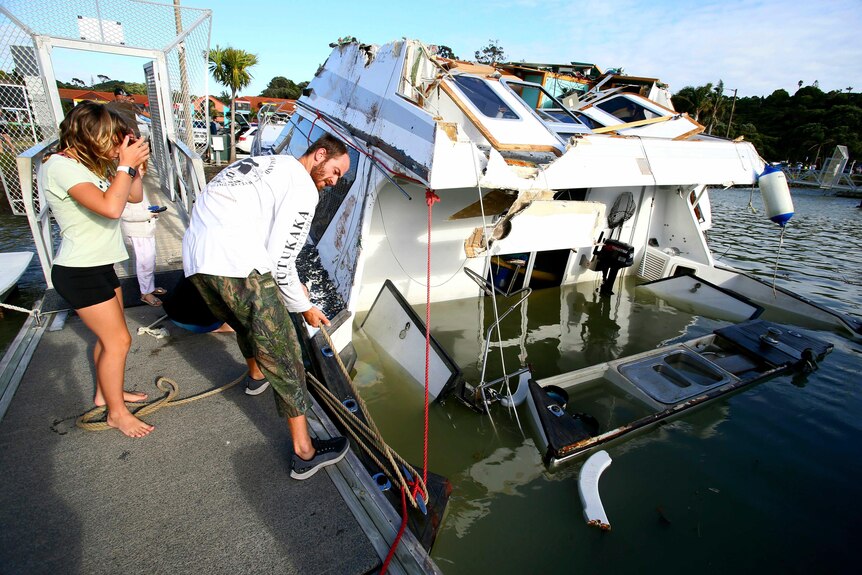 a man looks at a damaged boat.