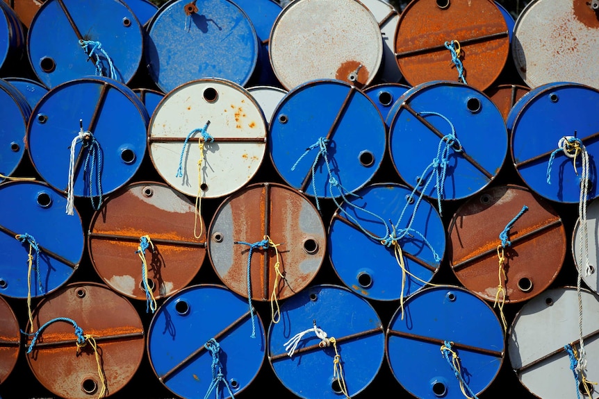 Rusty orange, white and blue oil barrels piled on top of each other