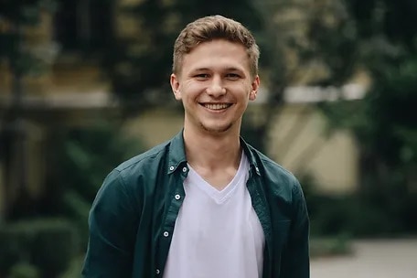 A professional headshot of a young man smiling.