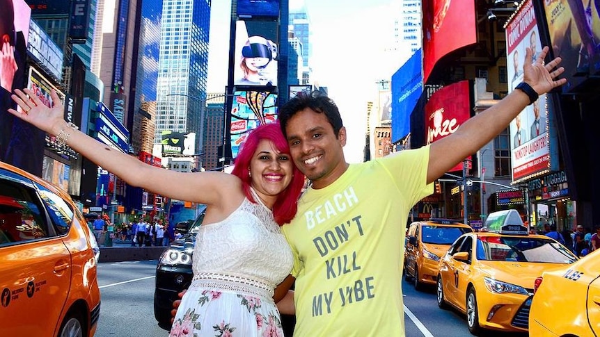 Meenakshi Moorthy, with bright pink hair, and her husband Vishnu Viswanath smile at the camera with their arms around each other