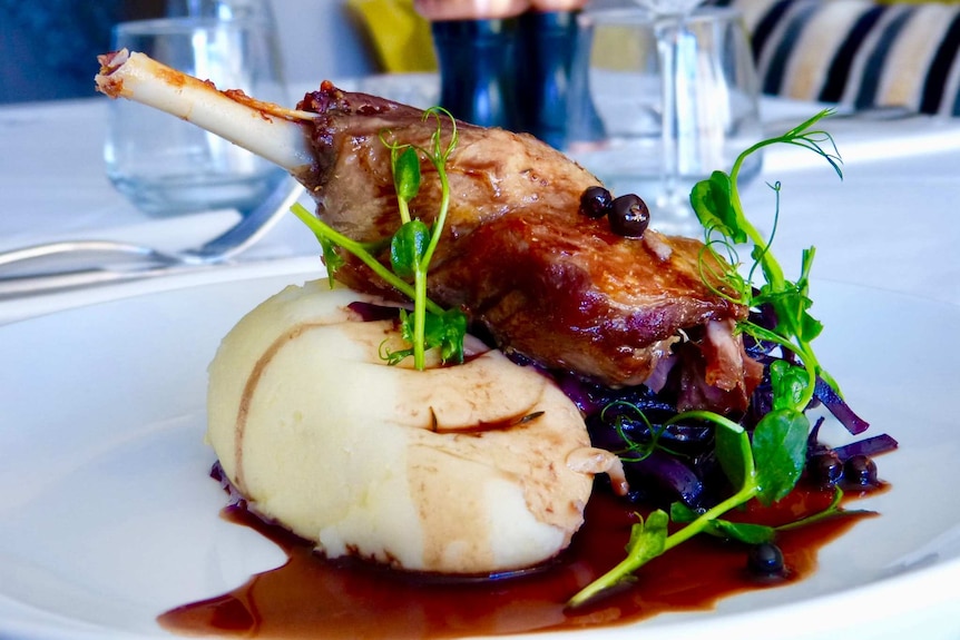 A plate of food on a table, with duck and potato.