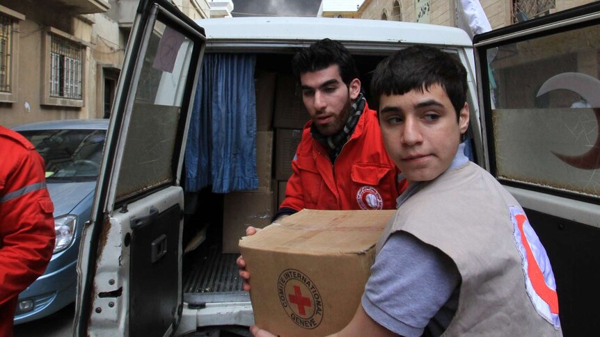 Men unload boxes from a four-wheel drive in Homs.