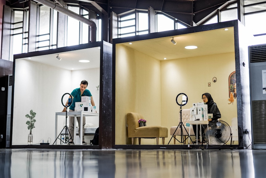 Two people looking busy in two different cubes.