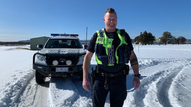 Tasmania Police Senior Constable Dan Adams stands in snow.