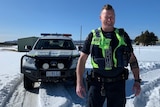 Tasmania Police Senior Constable Dan Adams stands in snow.