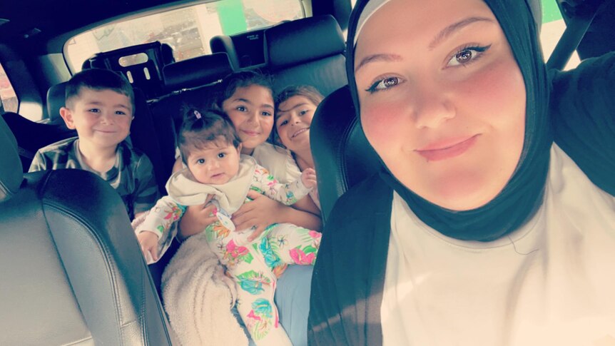 A photo of Samyaa (right) and four of her kids in the back seat of a car.