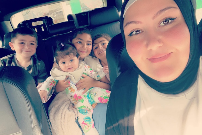 A photo of Samyaa (right) and four of her kids in the back seat of a car.