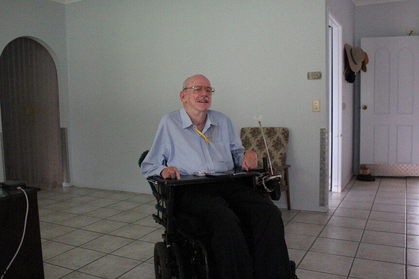 A man wearing a blue shirt in a wheelchair in the centre of an open living room