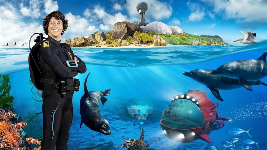 Andy wearing a wetsuit standing in front of some sea animals.