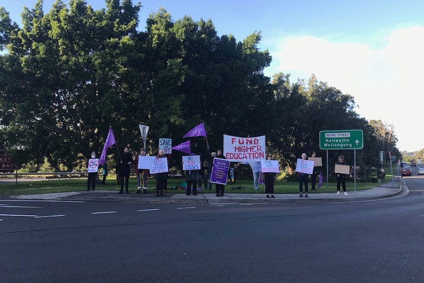 A dozen academics holding signs and banners protesting against cuts to the University of Wollongong.