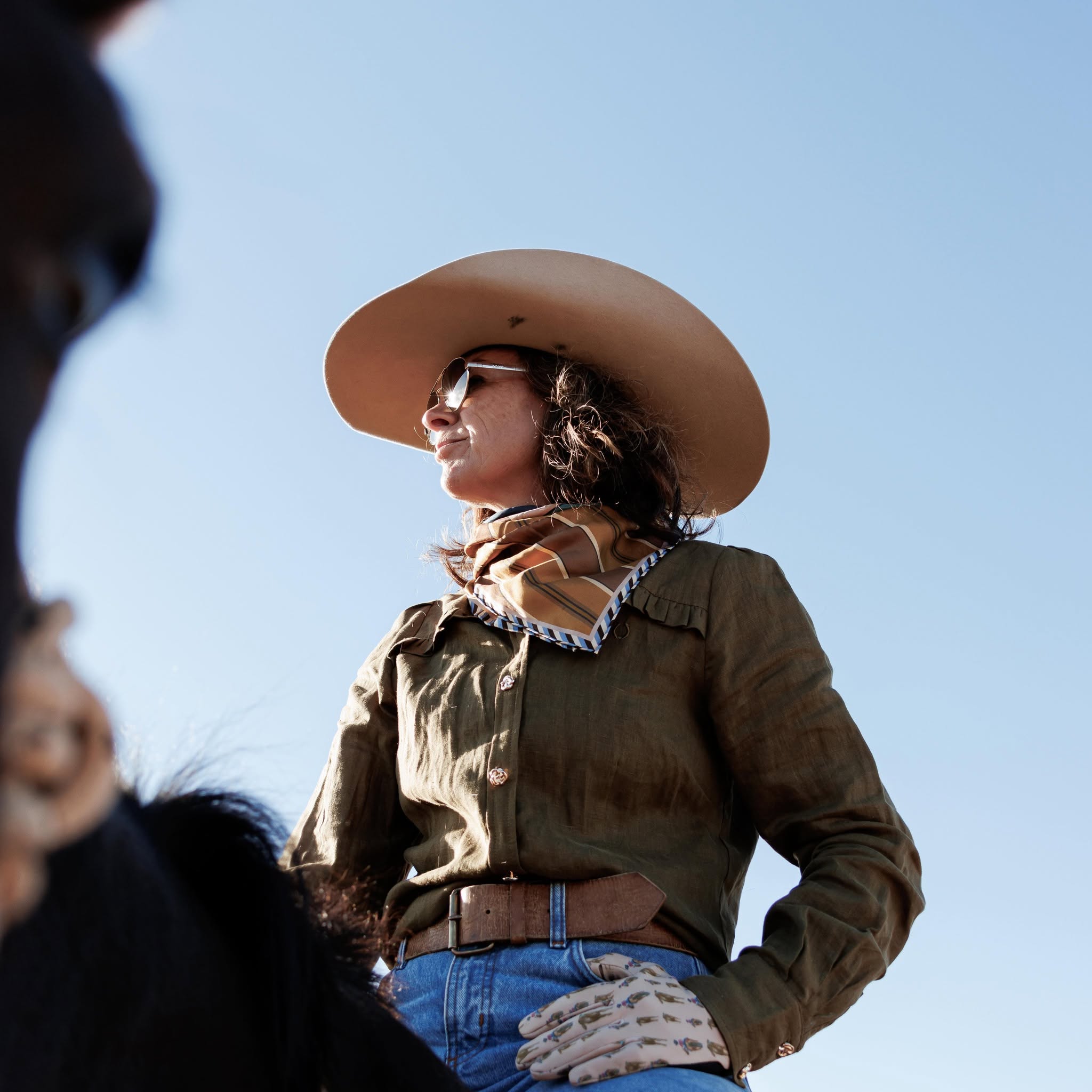 A woman in a wide-brimmed hat sits on horseback
