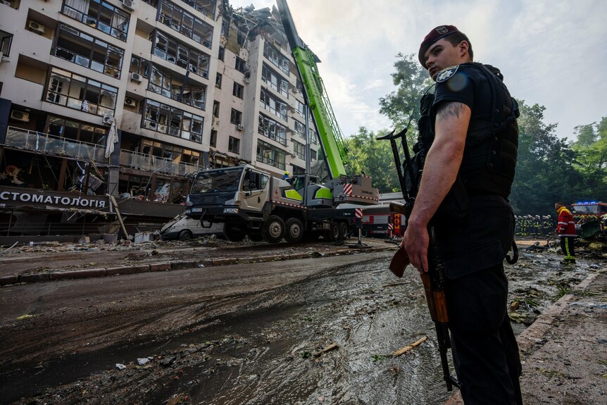 A Ukrainian policeman stands guard at the scene of a residential building following explosions, in Kyiv.