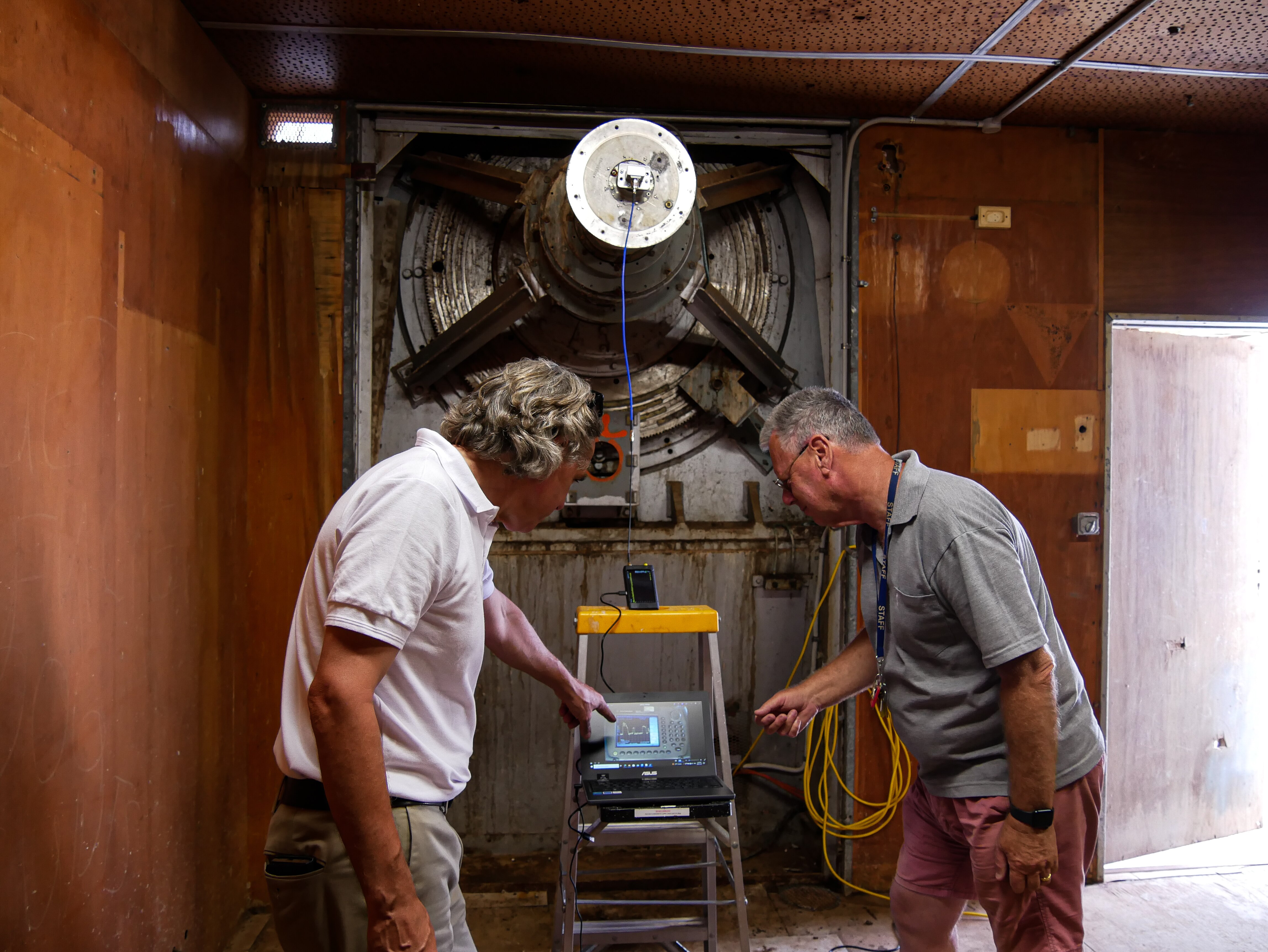 Two men look at a small screen.